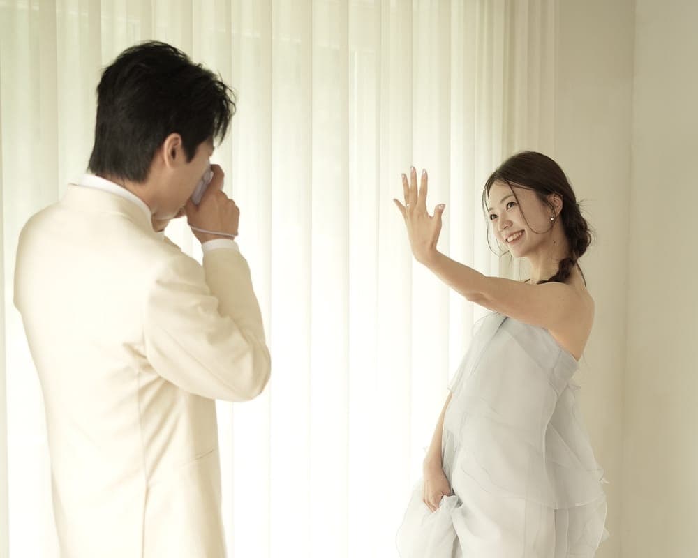 신랑이 즉석카메라로 찍는 동안 신부가 손을 흔들며 웃는 모습
